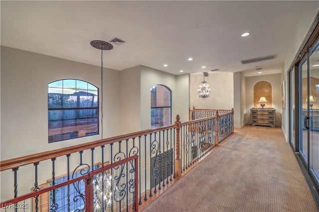 hallway featuring light colored carpet, recessed lighting, visible vents, and an inviting chandelier