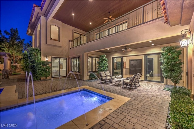 pool at night with a patio area, ceiling fan, and outdoor lounge area