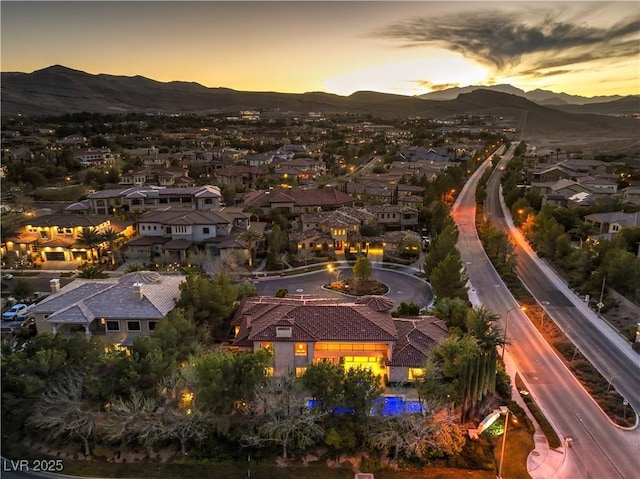 aerial view at dusk featuring a mountain view and a residential view