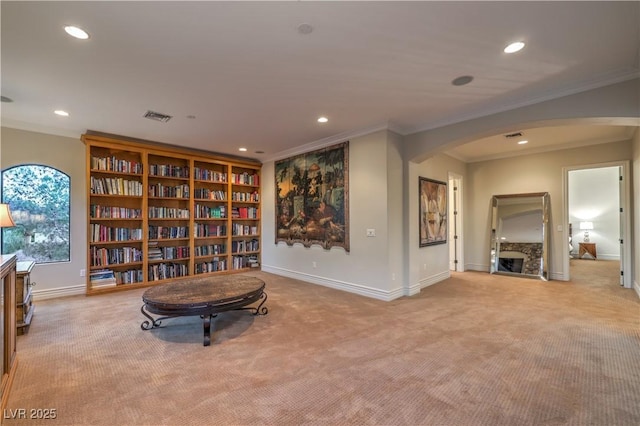 sitting room featuring ornamental molding, arched walkways, visible vents, and light colored carpet