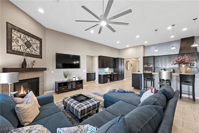 living area with light tile patterned floors, recessed lighting, a ceiling fan, and a glass covered fireplace