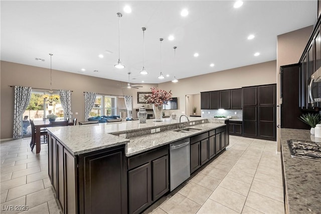 kitchen with light stone counters, a spacious island, a sink, appliances with stainless steel finishes, and decorative light fixtures