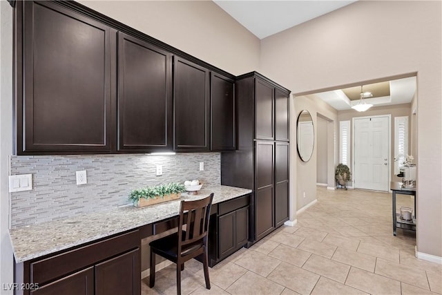 kitchen featuring light stone countertops, decorative backsplash, and dark brown cabinets