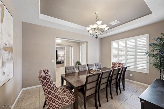 dining space featuring light tile patterned floors, visible vents, a tray ceiling, and baseboards