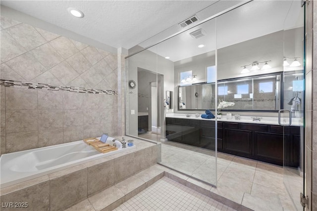 full bath with double vanity, visible vents, a bath, tile patterned flooring, and a sink