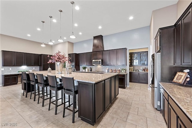 kitchen featuring appliances with stainless steel finishes, a spacious island, decorative light fixtures, and dark brown cabinetry