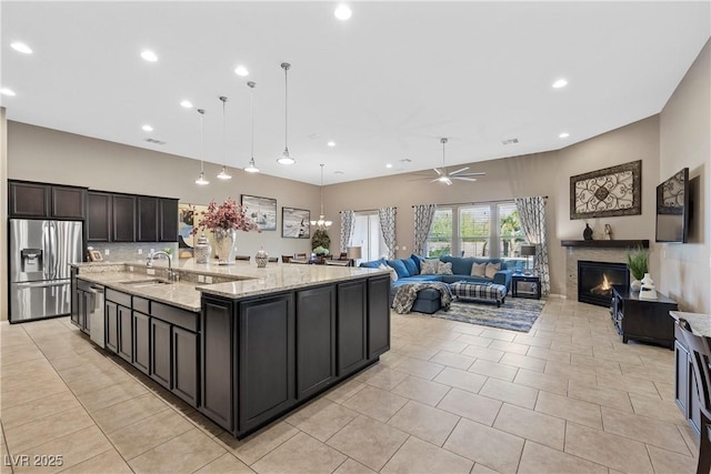 kitchen featuring stainless steel appliances, a spacious island, a sink, open floor plan, and pendant lighting