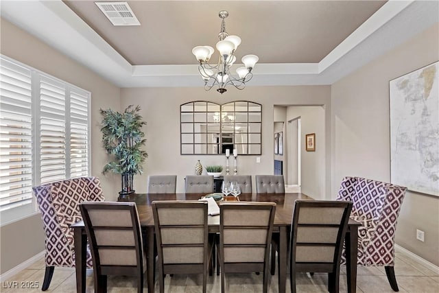 dining space with visible vents, baseboards, an inviting chandelier, a tray ceiling, and light tile patterned flooring