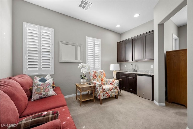 sitting room featuring light carpet, indoor wet bar, visible vents, and baseboards