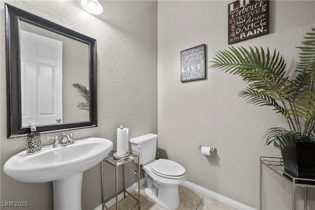 half bath with tile patterned flooring, baseboards, and toilet