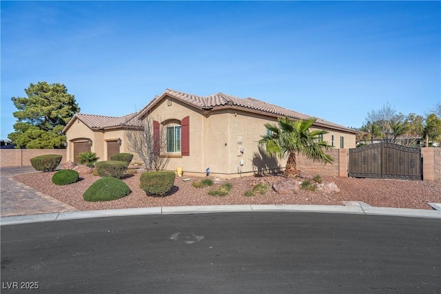 mediterranean / spanish house featuring a tile roof, an attached garage, fence, decorative driveway, and stucco siding