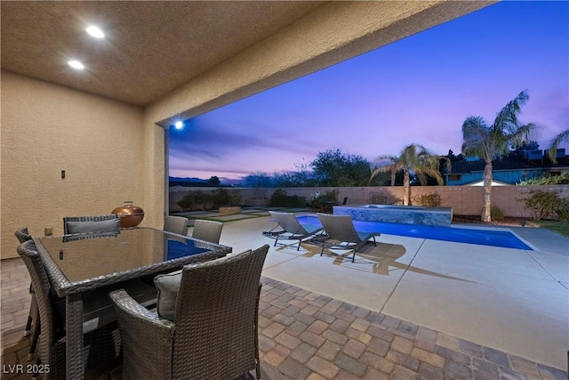 patio terrace at dusk with a fenced in pool and a fenced backyard