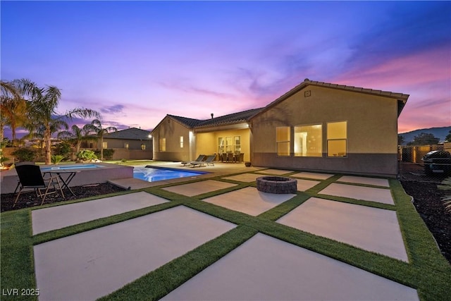 back of property featuring a fire pit, stucco siding, a patio area, and an outdoor pool