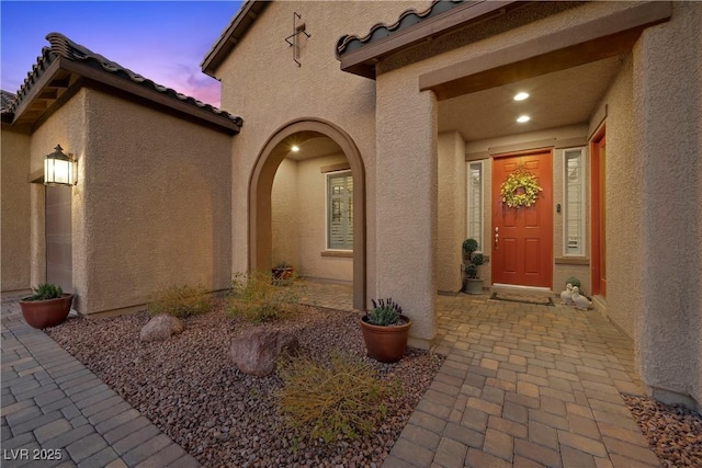 doorway to property featuring a tiled roof and stucco siding