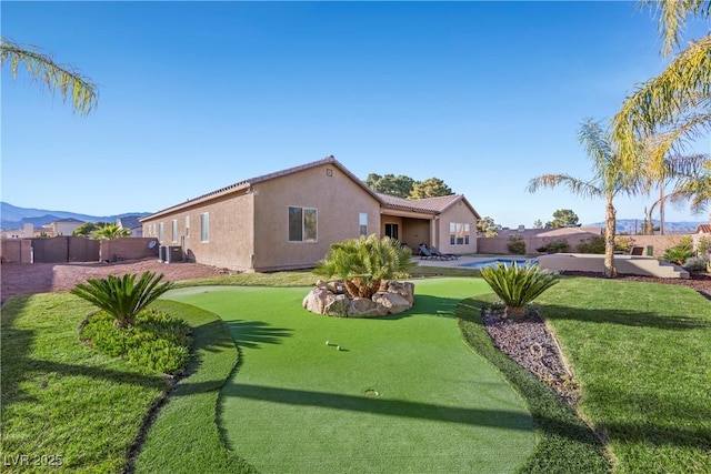 rear view of house with a fenced backyard, a mountain view, central AC, and stucco siding