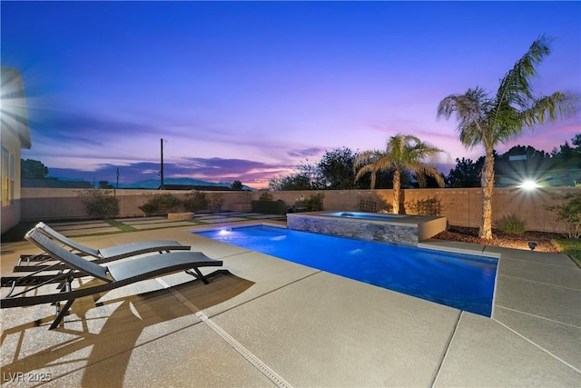 pool at dusk featuring a patio, a fenced backyard, a fenced in pool, and an in ground hot tub