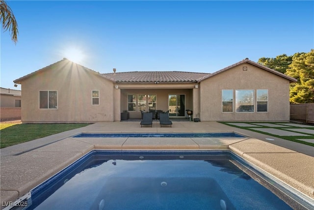 rear view of house featuring an outdoor pool, a patio, a tiled roof, fence, and stucco siding