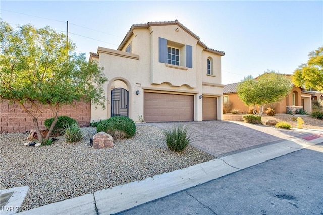 mediterranean / spanish home with decorative driveway, an attached garage, a tile roof, and stucco siding