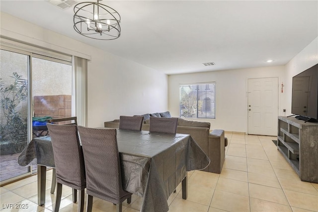 dining room with light tile patterned floors, visible vents, and a notable chandelier