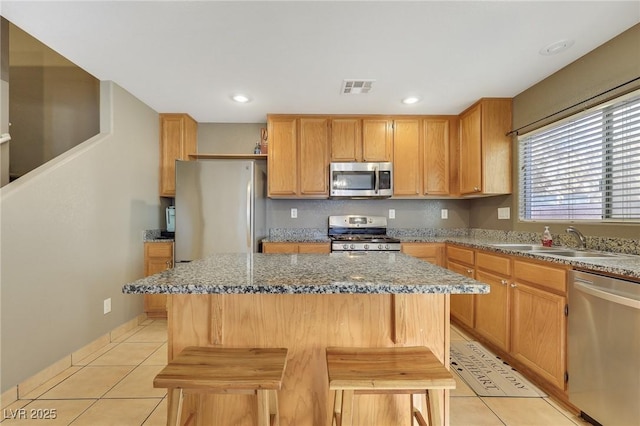 kitchen featuring a breakfast bar area, stainless steel appliances, visible vents, a kitchen island, and a sink