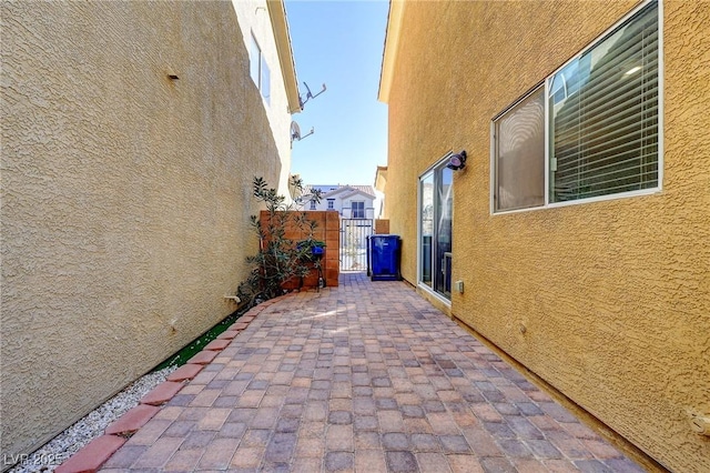 view of property exterior featuring a patio, fence, a gate, and stucco siding