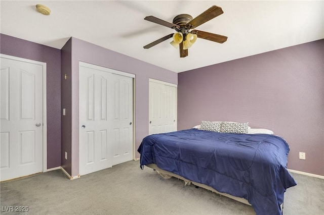 carpeted bedroom with multiple closets, baseboards, and a ceiling fan