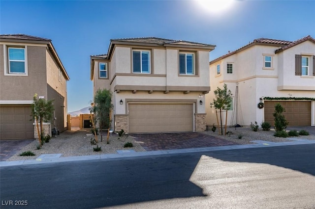 view of front of house with a garage, stone siding, decorative driveway, and stucco siding