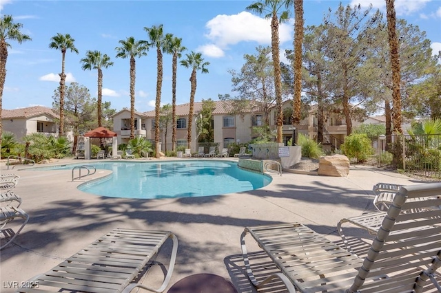 community pool with fence, a patio, and a residential view