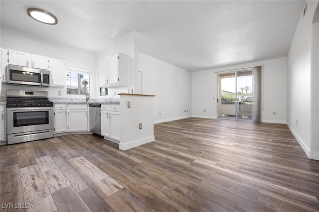 kitchen with white cabinetry, open floor plan, dark wood-type flooring, and stainless steel appliances