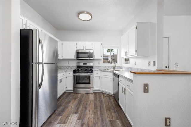 kitchen with dark wood-type flooring, white cabinetry, a sink, and appliances with stainless steel finishes