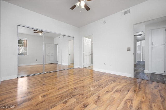 unfurnished bedroom featuring a ceiling fan, wood finished floors, baseboards, and visible vents