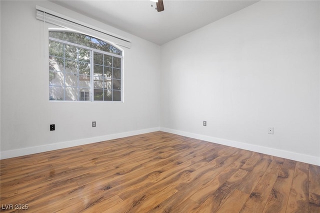 empty room featuring a ceiling fan, baseboards, and wood finished floors