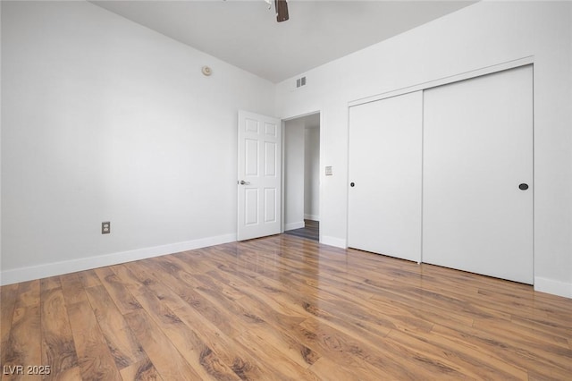 unfurnished bedroom with a closet, wood finished floors, and baseboards