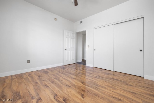 unfurnished bedroom with baseboards, a closet, and wood finished floors