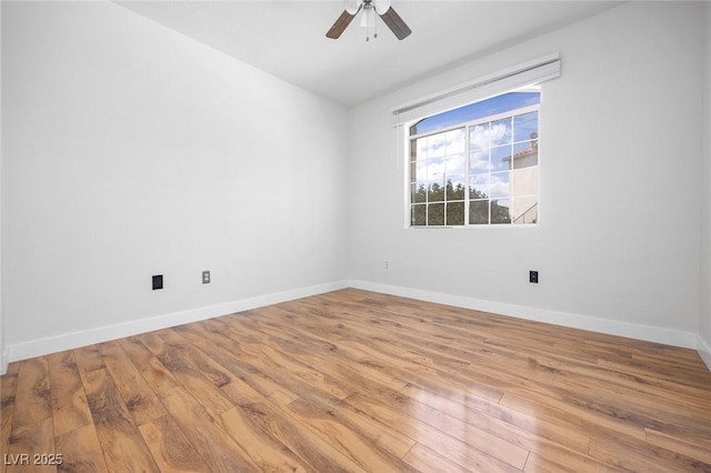 spare room with wood finished floors, a ceiling fan, and baseboards