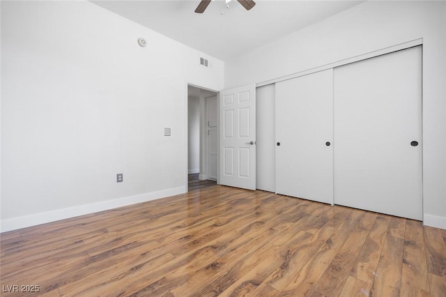 unfurnished bedroom with baseboards, visible vents, a ceiling fan, a closet, and wood finished floors