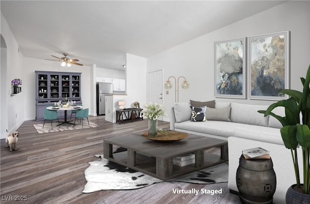 living area featuring arched walkways, baseboards, wood finished floors, and a ceiling fan