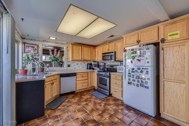 kitchen with stainless steel appliances, light countertops, visible vents, light brown cabinetry, and a sink