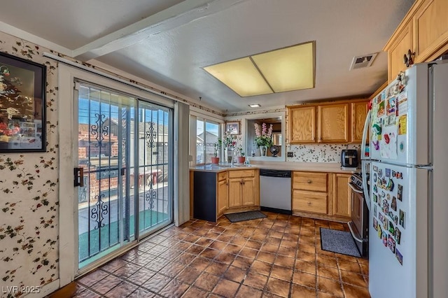 kitchen featuring visible vents, appliances with stainless steel finishes, light countertops, light brown cabinets, and a sink