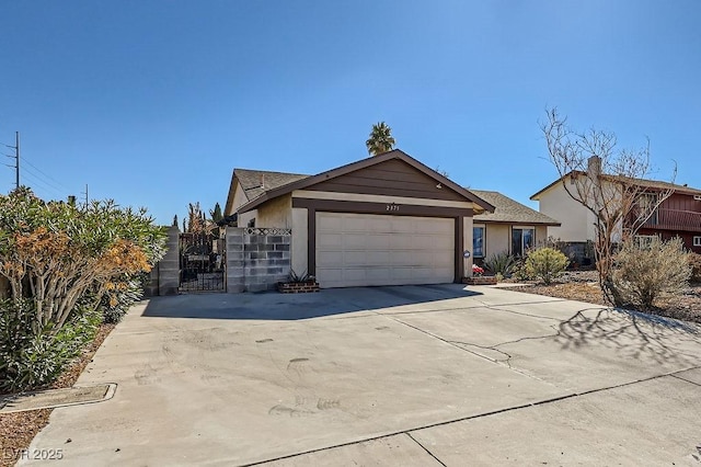 view of front facade with concrete driveway, an attached garage, a gate, and stucco siding