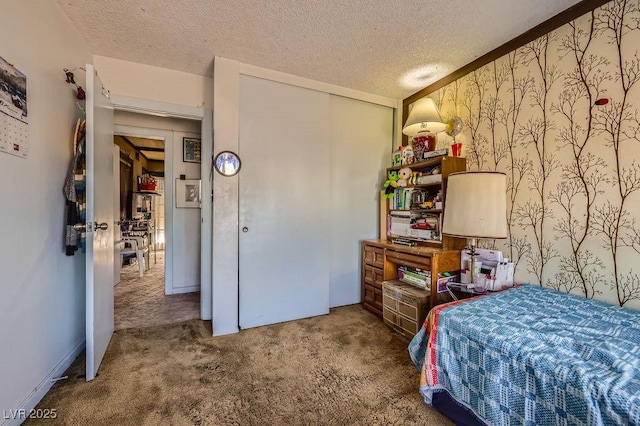 bedroom with wallpapered walls, carpet, a closet, and a textured ceiling