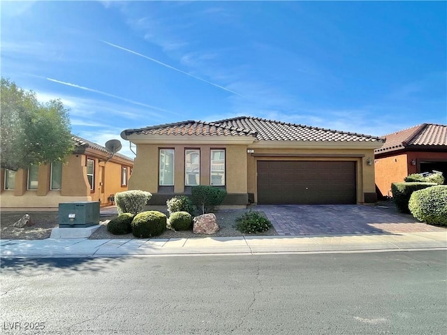 view of front of home featuring a garage, central air condition unit, decorative driveway, and stucco siding