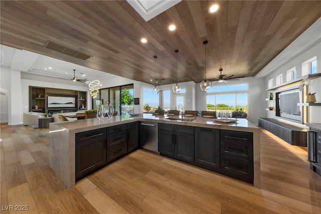 kitchen with a sink, open floor plan, hanging light fixtures, dishwasher, and light wood finished floors