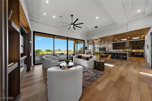 living area featuring a tray ceiling, wood-type flooring, visible vents, and recessed lighting