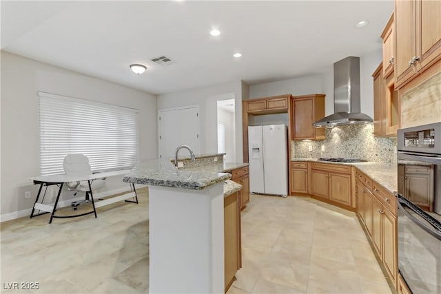 kitchen featuring stainless steel gas cooktop, dobule oven black, a kitchen island with sink, white fridge with ice dispenser, and wall chimney exhaust hood