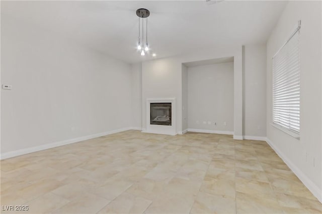 unfurnished living room with a glass covered fireplace and baseboards