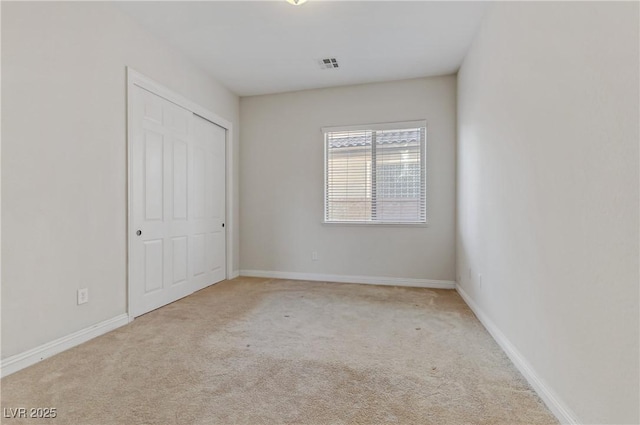 unfurnished bedroom featuring light carpet, baseboards, visible vents, and a closet