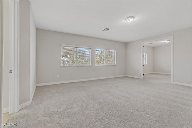 empty room featuring light carpet, visible vents, and baseboards