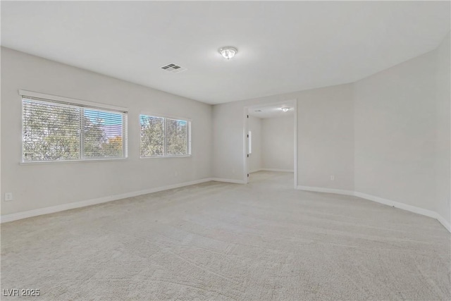 spare room featuring light colored carpet, visible vents, and baseboards