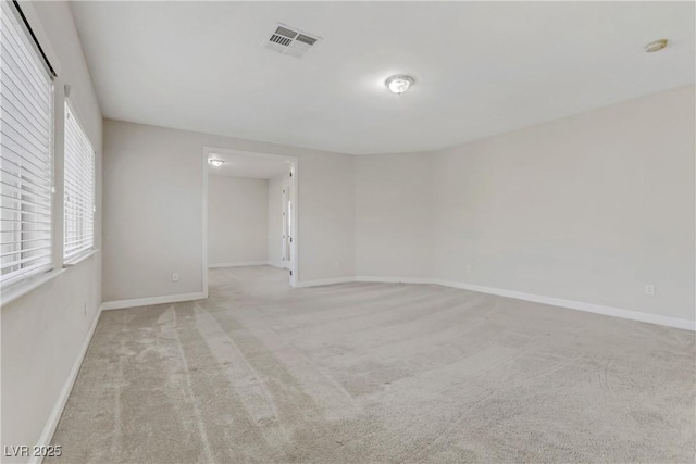 empty room featuring light colored carpet, visible vents, and baseboards